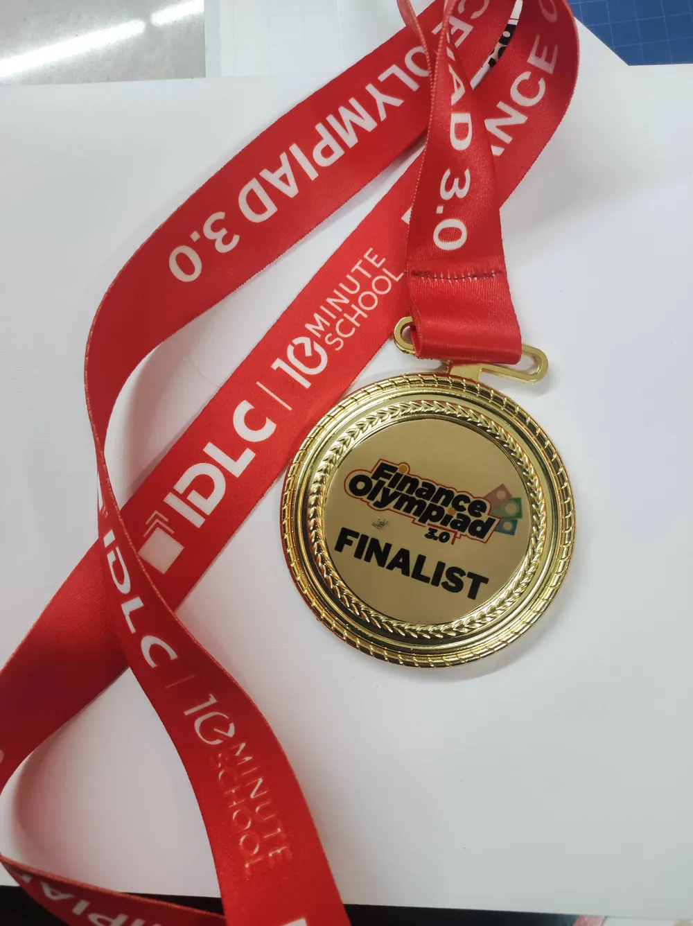 Finalist medal on a red lanyard printed IDLC, 10 Minute School and Finance Olympiad 3.0