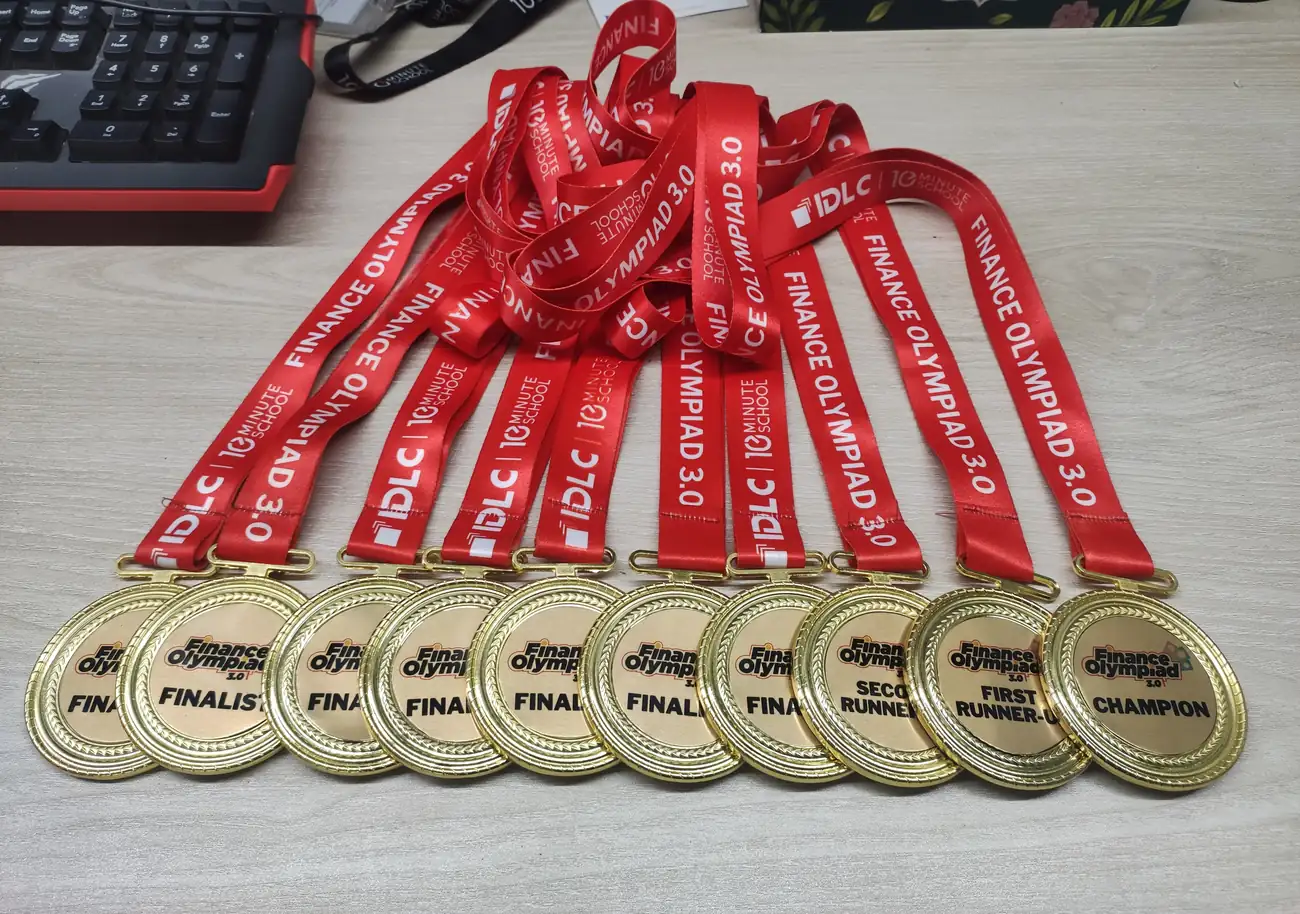 Ten finalist and champion medals laid out on red Finance Olympiad 3.0 lanyards