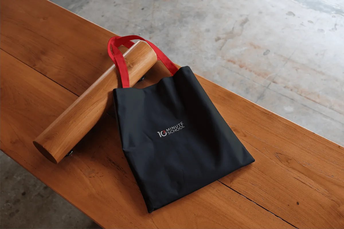 Black tote bag with red handles on a wooden bench