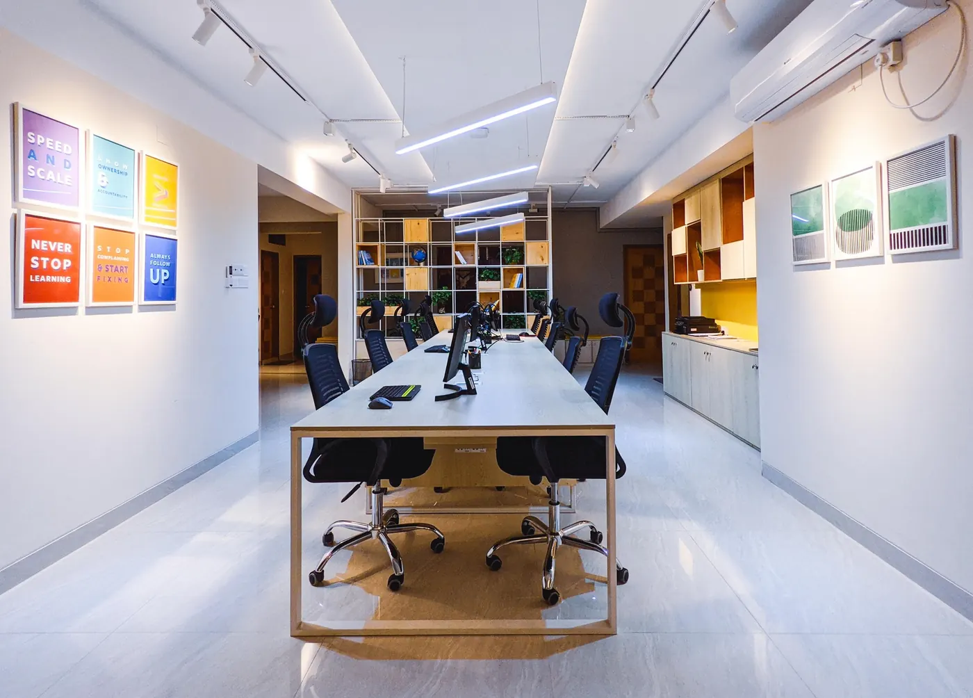 Long work table under a wall of brand posters