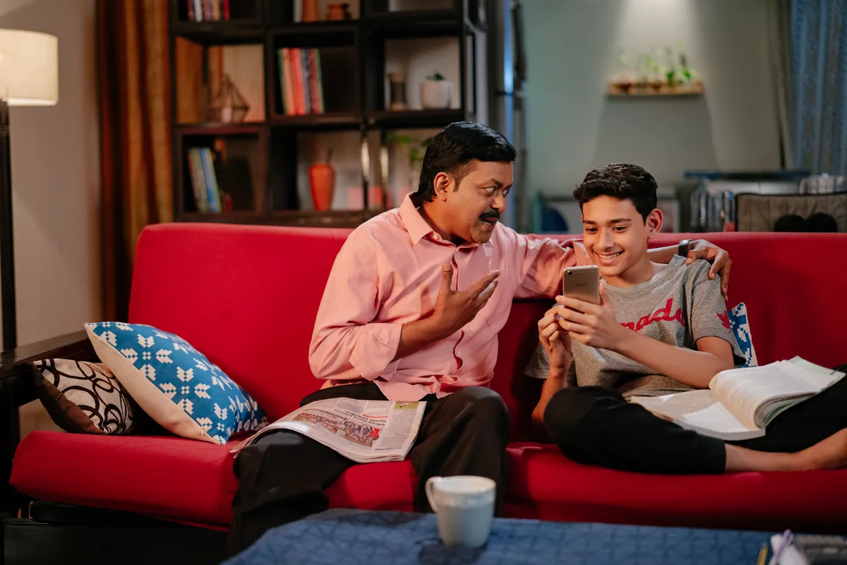 10 Minute School campaign photo of father and son on red sofa