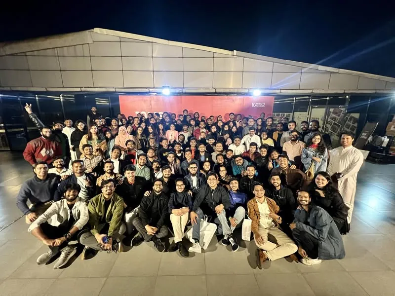 The whole 10 Minute School team on the rooftop at night, in front of the red 10MS backdrop