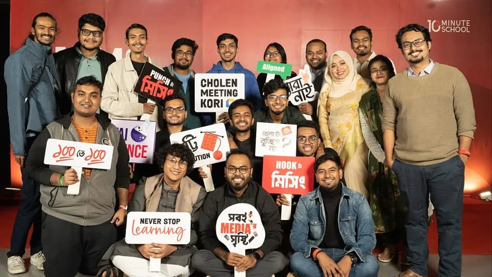 The team in front of the red 10MS backdrop holding up the placards